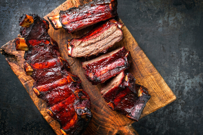Barbecue chuck beef ribs with hot marinade as top on a wooden cutting board